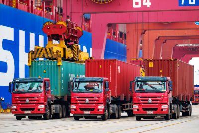 A crane vehicle lifts a container to be shipped abroad from a truck on a quay at the port of Qingdao in Qingdao city, east China's Shandong province, 11 July 2019 (Photo: Reuters).